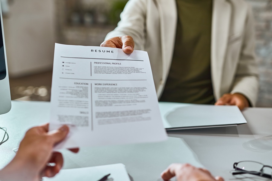 Close-up of job applicant giving his resume during job interview in the office.